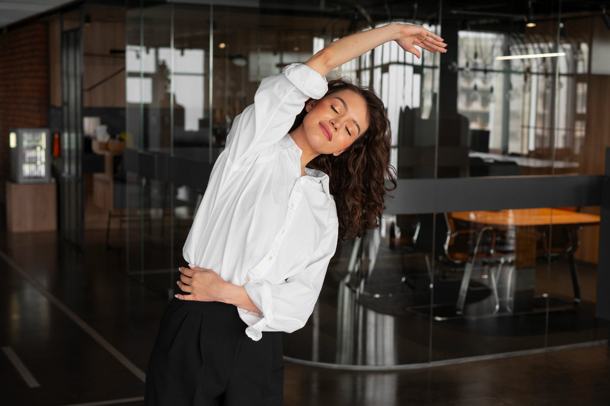 Comfortable women's athletic work dress pants showcased by a woman stretching in a corporate office