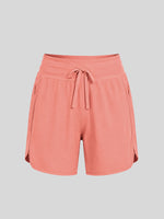 A pair of women's coral pink athletic shorts with an elastic waistband, drawstring, and side pockets 