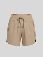 A pair of women's beige athletic shorts with an elastic waistband, drawstring, and side pockets 