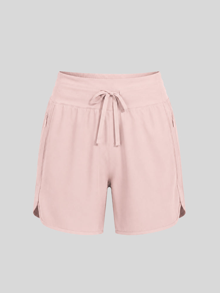 Women's light pink athletic shorts with a drawstring waist, side pockets, and side gussets 