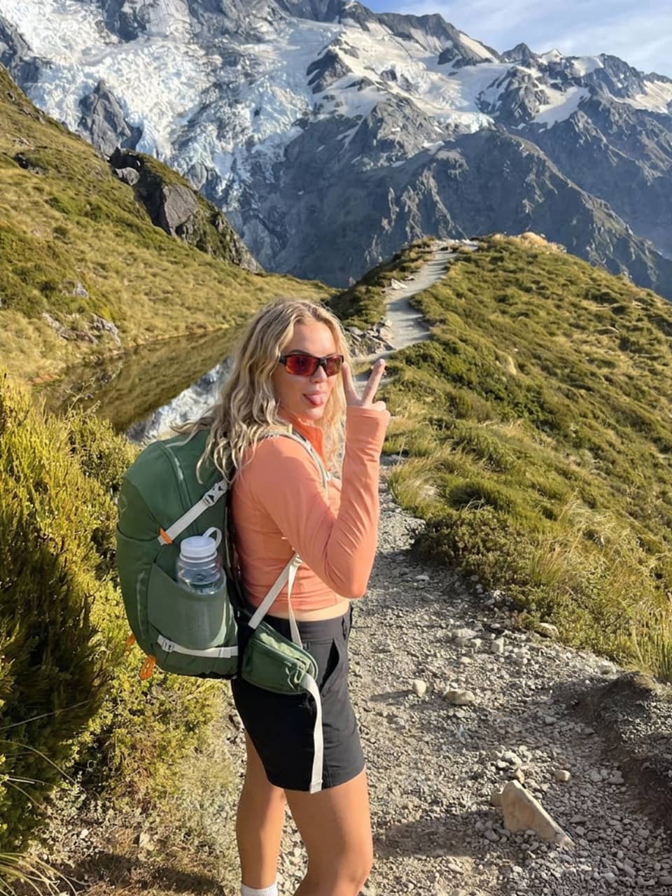 UGC content-woman hiking on a mountain trail wearing a willit women's peach long-sleeve crop top, willit women's black cargo shorts
