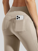 Close-up of a model wearing high-waisted beige leggings with a side pocket holding a phone 