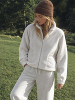 A woman wearing a cozy cream-colored fleece zip-up jacket and matching sweatpants 