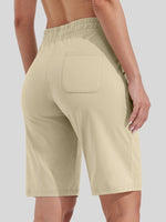 A close-up back view of a women wearing light beige cotton bermuda shorts with an elastic waistband and a single back pocket 