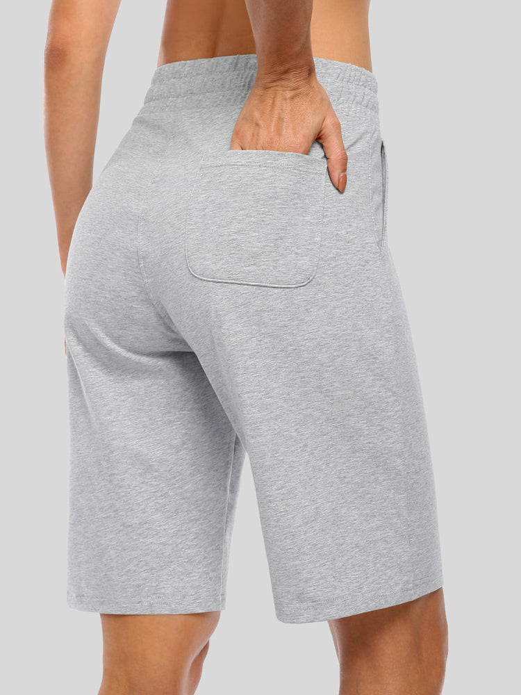 A close-up back view of a women wearing light heather gray shorts, with one hand in the back pocket 