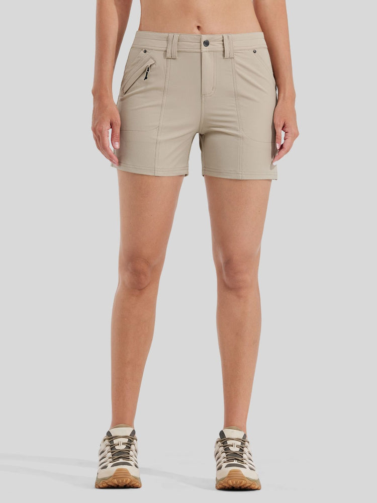 A model from the waist down wearing light beige athletic shorts with zippered pockets and hiking shoes 