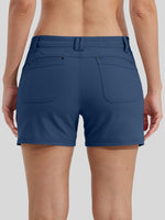 Rear view of a woman wearing blue athletic shorts with two large back patch pockets 