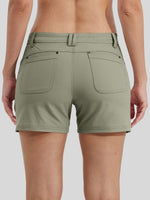 A back-view close-up of a woman wearing olive green outdoor shorts with side pockets and a button closure  