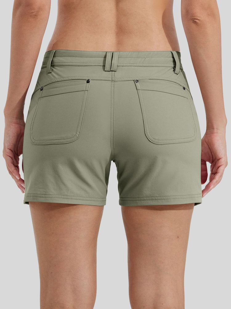 A back-view close-up of a woman wearing olive green outdoor shorts with side pockets and a button closure  