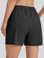 Rear view of a woman wearing black cargo-style athletic shorts with an elastic waistband and side cargo pocket 
