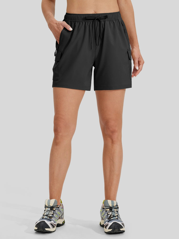 A model wearing black athletic shorts with side cargo pockets and a drawstring waist, paired with trail running shoes 