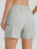 A close-up back view of a female model wearing light gray athletic shorts with an elastic waistband and a side cargo pocket 