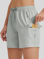 A close-up of a model wearing light gray drawstring shorts with a large front cargo pocket 