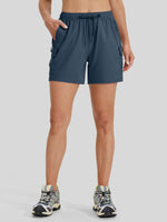 A model wearing slate navy athletic shorts with side cargo pockets and a drawstring waist 