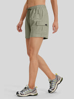 A model wearing sage green cargo shorts and hiking shoes 