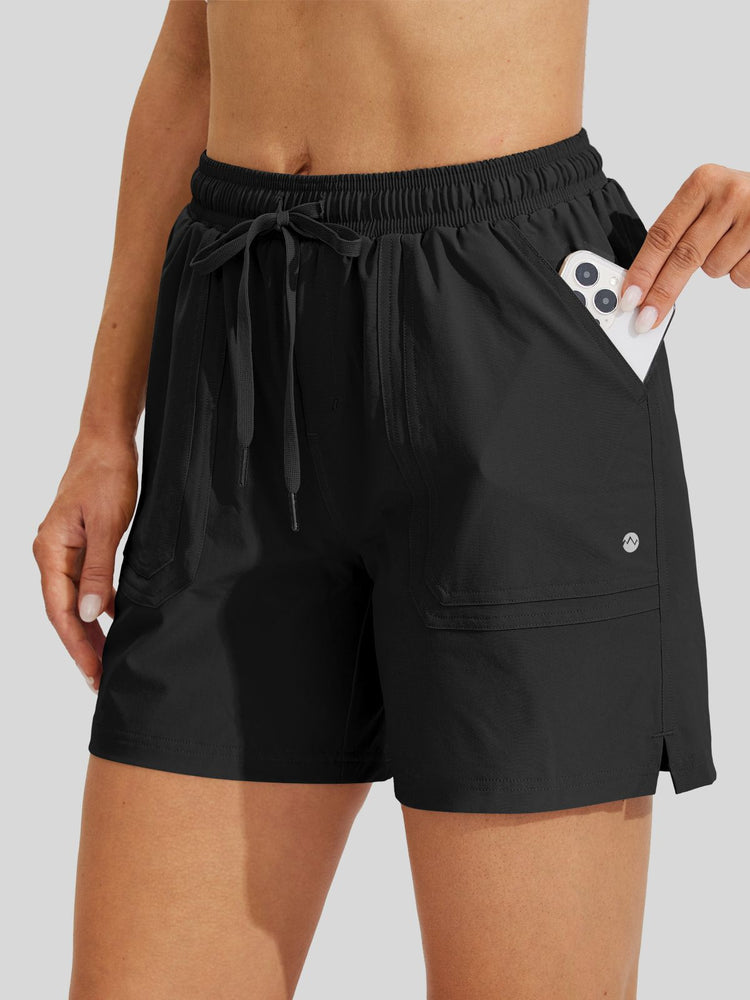 Women's black athletic shorts with an elastic drawstring waist and side pocket holding a phone 