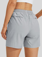 A close-up back view of a women wearing light gray athletic shorts with an elastic waistband and side pockets 