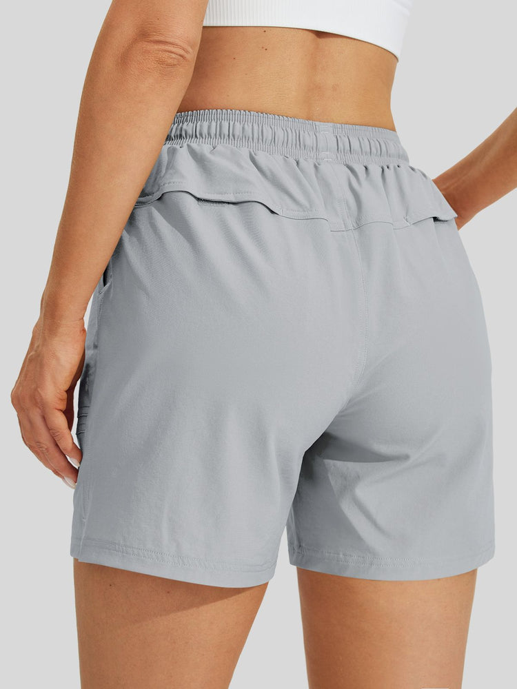 A close-up back view of a women wearing light gray athletic shorts with an elastic waistband and side pockets 