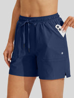 women wearing navy blue drawstring shorts with a side pocket holding a white smartphone 
