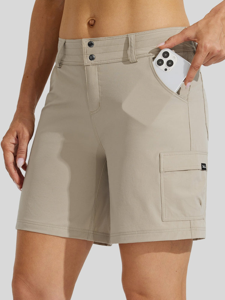 A close-up of a woman wearing beige cargo shorts with a side pocket holding a phone. The shorts feature a double-button closure at the waist, belt loops, and a cargo pocket on the lower right leg. 