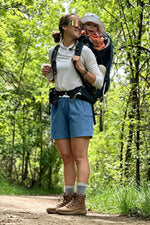 Woman hiking with a child in a backpack in a forest 